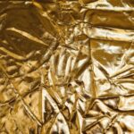 High-resolution image of crumpled gold fabric, perfect for backgrounds and designs.